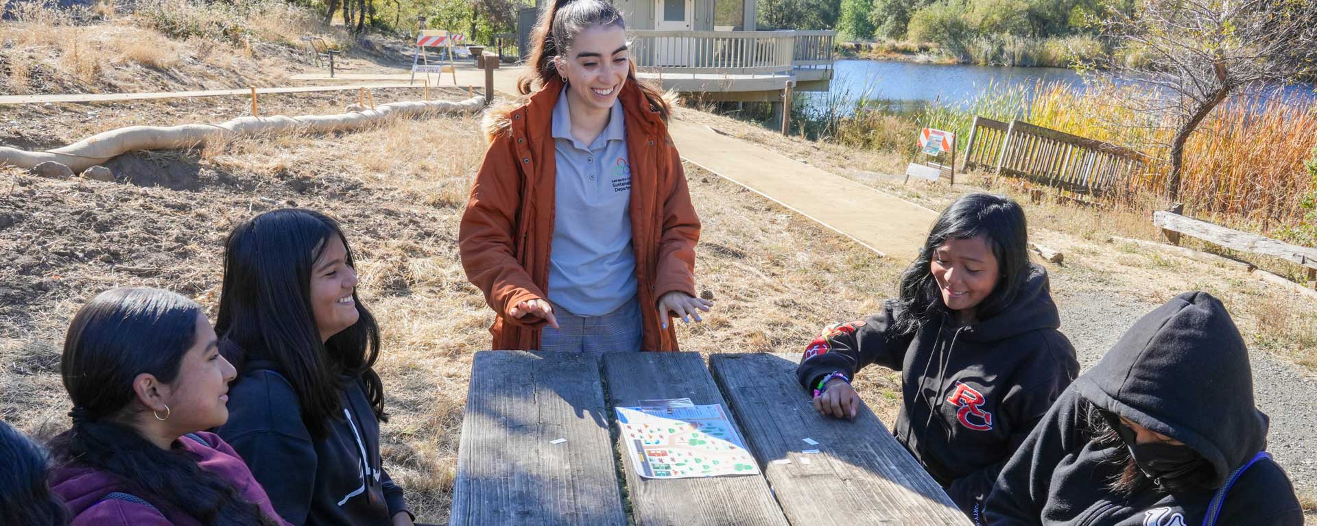Sustainability Department educator teaching students an activity at a park picnic table
